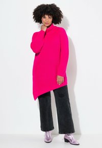 Fuchsia Rollkragenpullover mit strukturiertem Strick und asymmetrischem Saum. Kombiniert mit schwarzen weit geschnittenen Jeans und metallischen Ankle Boots.