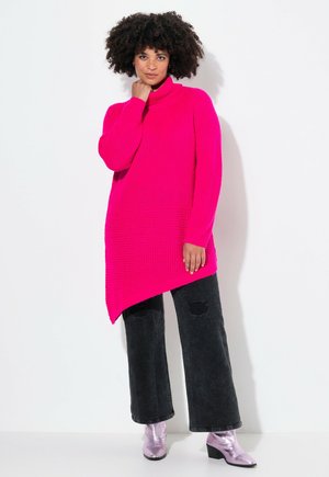 Fuchsia Rollkragenpullover mit strukturiertem Strick und asymmetrischem Saum. Kombiniert mit schwarzen weit geschnittenen Jeans und metallischen Ankle Boots.