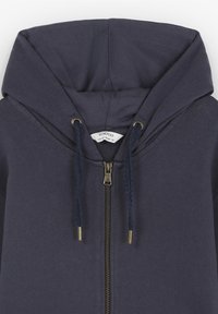 Sudadera con cremallera en color navy, con capucha ajustable mediante cordón, que presenta una cremallera metálica y detalles en tono dorado. Tejido suave con una textura lisa.