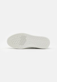 White rubber shoe sole featuring a honeycomb pattern, textured surface, and multiple drainage holes for improved traction and flexibility.