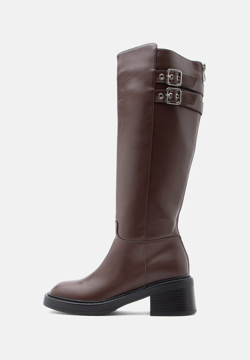 Bottes hautes jusqu'au genou en cuir marron avec un bout arrondi, un talon bloc et deux boucles en argent en haut. Texture lisse et design élégant.