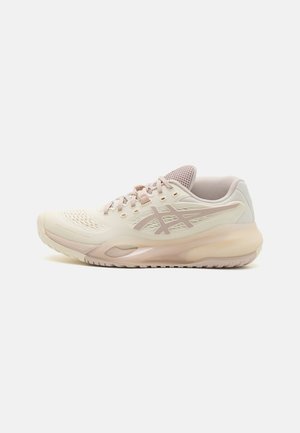 Light pink athletic shoe with a textured upper, mesh tongue, and a cushioned sole. Features a prominent logo and streamlined design.