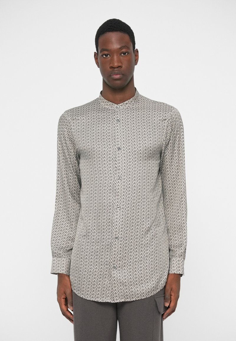 Μακρυμάνικη πουκάμισο με κουμπιά που διαθέτει γεωμετρικό σχέδιο σε μαύρο και μπεζ, με κολάρο band και �χαλαρή εφαρμογή, φτιαγμένο από ελαφρύ ύφασμα.