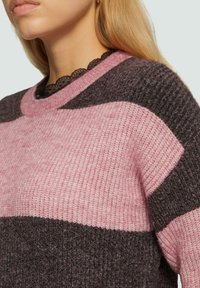 Gebreide trui met roze en donkergrijze kleurvlakken, ronde halslijn en een textuurstof met een subtiel geribbeld patroon.