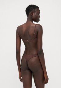 Brun ribbet bikini-set med tynne justerbare stropper, en metallklips bak, og en lave-ris thong-bunn. Glatt tekstur.