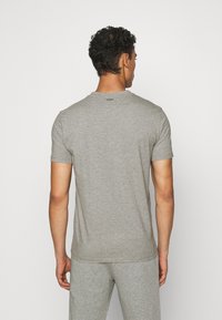 Tricou gri cu mânecă scurtă, realizat dintr-un material moale, cu un guler de tip crew și un design minimalist, având un logo pe spate.