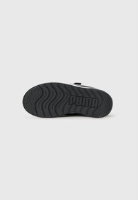 Semelle de sneaker noire en caoutchouc texturé pour une bonne adhérence, présentant un motif ondulé et un logo de marque en relief. Design épuré sans signes d'usure visibles.