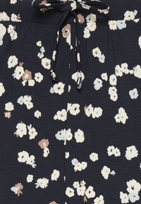 Mörk marinblått tyg med blommönster i vitt, beige och ljusblått. Har dragsko i midjan och mjuk textur.