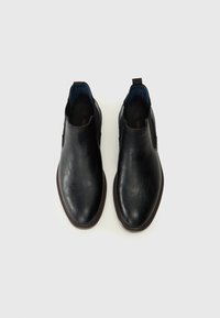 Chaussures noires en cuir à enfiler avec une texture lisse, bout rond et doublure intérieure bleue contrastante. Caractéristiques de tirettes pour un enfilage facile.