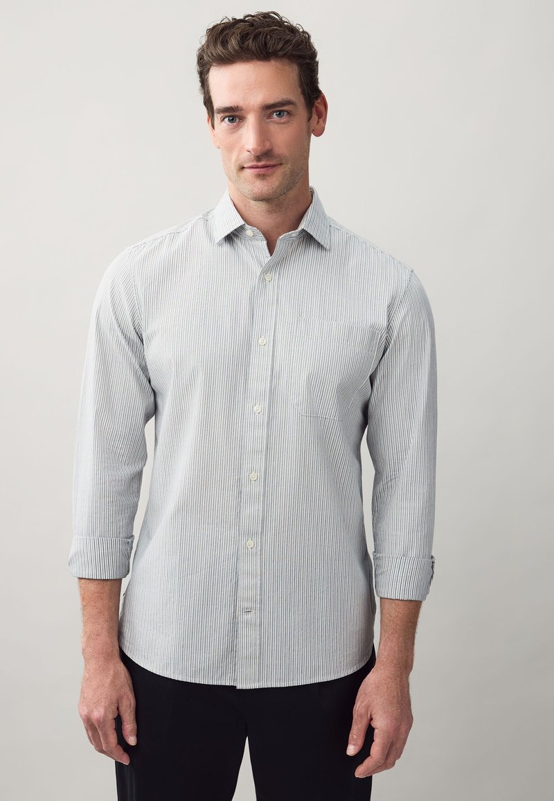Camicia a righe azzurro chiaro e bianco con bottoni, maniche lunghe, colletto e taschino sul petto, realizzata in un tessuto liscio.