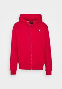 Rode zip-up hoodie gemaakt van zacht stof, met een kangoeroezak, een capuchon met trekkoord en een klein geborduurd logo op de borst.