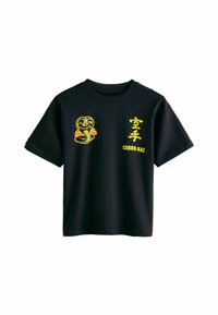 Sort bomulds t-shirt med et gult kobra grafisk motiv og "Cobra Kai" tekst på forsiden. Korte ærmer og klassisk crew neck design.