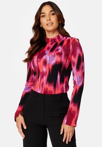 Langarmtop in een kleurrijk abstract patroon met tinten roze, paars en zwart, met een geribbelde textuur en hoge hals.