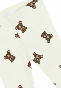 Strømpebukser i blødt, ribbet stof med en lys cremefarve og et gentaget mønster af brune bamser. Elastisk taljebånd for komfort.