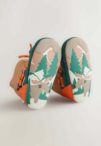 Braune Schuhe mit orangefarbenen Akzenten, ausgestattet mit einer strukturierten Rückseite und einer illustrierten Sohle, die Bäume und einen Elch darstellt. Schnürdesign mit bunten Schnürsenkeln.
