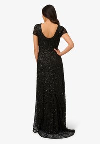Abito da sera nero con scollo basso, maniche corte e design aderente. Ricoperto di paillettes per aggiungere texture e brillantezza.