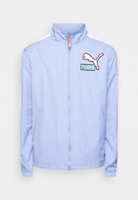 Chaqueta de cremallera azul claro con cuello alto, franjas laterales blancas y logotipo bordado de Puma en el pecho. Cuenta con puños y dobladillo elásticos.
