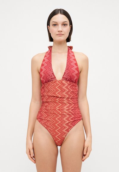 Rød og orange mønstret heldragt badedragt med en dyb udskæring, halterneck stropper og tekstureret zigzag-design på glat stof.