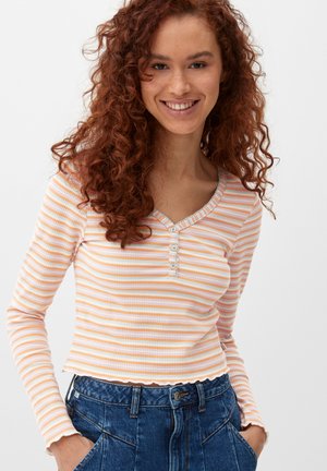 Langärmliges Rippoberteil in pastellorange und weißen Streifen, mit einem Henley-Ausschnitt mit Knöpfen und einem cropped Saum. Strukturierter Stoff.