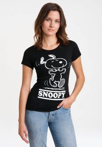 Camiseta de algodón negra con un gráfico blanco de Snoopy y el texto "SNOOPY" debajo. Mangas cortas y cuello redondo.