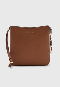 Bruine tas van synthetisch leer met een plat ontwerp, hardware in goudkleur en een verstelbare riem. Heeft een logo aan de voorkant en een gladde textuur.