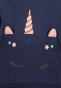 Felpa blu navy con un design di unicorno, dotato di un corno rosa a spirale, orecchie luccicanti e stelle in colori pastello.