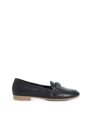 Mocasín de cuero negro con tacón bajo de madera y tira decorativa sobre la parte superior, mostrado de perfil sobre fondo blanco.