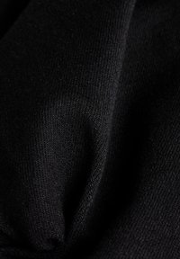 Schwarzer Stoff mit einem glatten, leicht strukturierten Gewebe. Das Material zeigt subtile Falten, die Weichheit und Flexibilität anzeigen. Keine sichtbaren Muster.