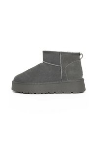 Botines de ante gris con forro suave, suela de goma plana y tirador. Presentan costuras detalladas y una textura suave.