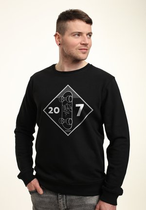 Felpa nera con grafica a forma di diamante che presenta i numeri "20" e "7", insieme a un'illustrazione di skateboard in bianco.