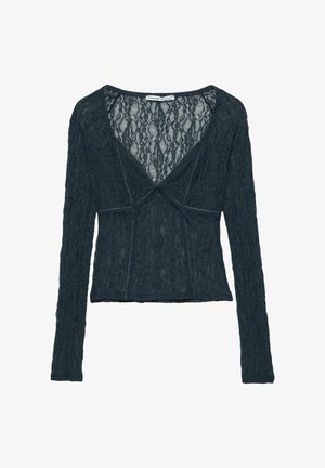 Langärmliges Oberteil aus dunkeltürkisfarbener Spitze, mit V-Ausschnitt, tailliertem Oberteil und kontrastierenden Nähten entlang der Nähte und des Ausschnitts.
