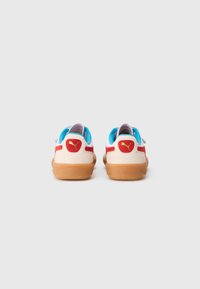 Sneakers Puma z białą cholewką, czerwonymi akcentami, niebieskim wnętrzem i gumową podeszwą. Posiadają logo na pięcie oraz niskoprofilowy design.