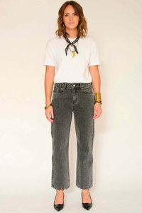 Jean en denim noir et gris à jambes larges avec un ourlet effiloché et une taille haute, porté avec un t-shirt blanc et un foulard noir noué autour du cou.