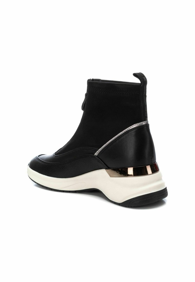 Bottines noires en daim avec une finition texturée, présentant un accent métallique sur le talon et une semelle en caoutchouc blanc.