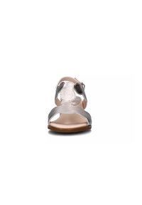 Sandalia plateada y gris con un acabado de cuero suave, diseño de punta abierta, tira en el tobillo y suela plana marrón. Cuenta con un acento texturizado.