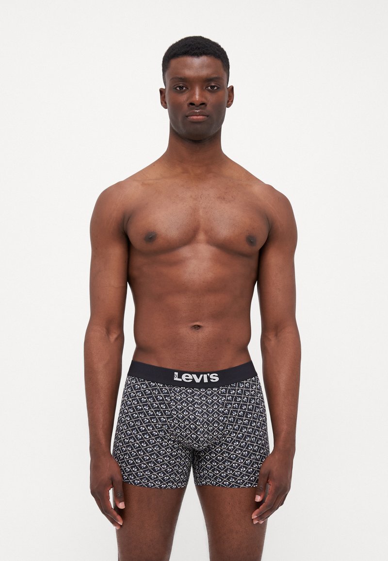 Crne bokserice s uzorkom i elastičnim pojasom s Levi's logom, koje imaju geometrijski dizajn i uski kroj. Tekstura izgleda mekano i rastezljivo.
