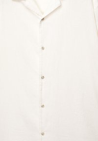 Lichtgekleurde blouse met knopen, gemaakt van gestructureerde stof, met een kraag en meerdere knopen aan de voorkant.