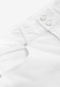 Witte denim stof met een voorkant met opening, voorzien van twee zilveren knopen en een kleine metalen accent. Glad oppervlak met zichtbare stiksels.