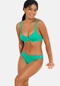 Ensemble de bikini vert comprenant un soutien-gorge rembourré avec un centre froncé et des bretelles réglables, associé à un bas de bikini taille basse. Texture lisse.