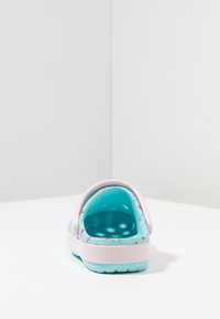 Een achteraanzicht van een lichtgewicht, turquoise en roze instapschoen met een roze band en een flamingo-patroon aan de binnenkant.