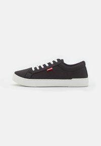 Zapatillas de lona negras con cordones blancos, que cuentan con una suela de goma resistente y un pequeño logo rojo de Levi's en el lateral. Diseño de punta redondeada y plana.