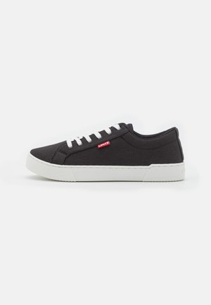 Czarne płócienne sneakersy z białymi sznurówkami, z solidną gumową podeszwą i małym czerwonym logo Levi's po boku. Płaska, zaokrąglona cholewka.