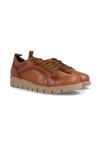 Zapatillas de piel marrón con cordones verdes, punta redondeada y suela plana beige con surcos visibles y detalles de costura. Textura suave.