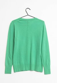 Maglione a maniche lunghe verde in maglia con scollo rotondo appeso a una gruccia nera su sfondo bianco.