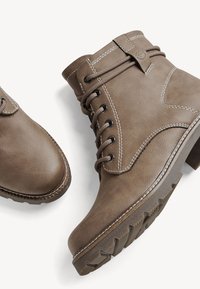 Brown leather ankle boots with laces, contrasting stitching, rounded toe, and rugged rubber sole featuring a textured pattern.