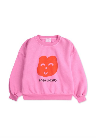 Pink sweatshirt with a red smiley face graphic and "BOBO CHOSES" text. Features long sleeves and ribbed cuffs and hem. Soft texture.
