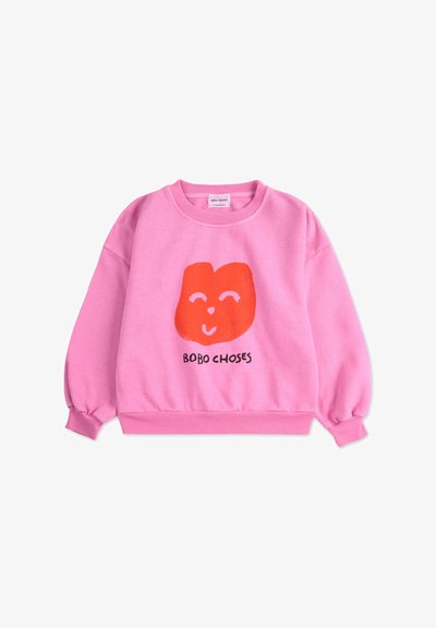 Sweatshirt rose avec un graphique de visage souriant rouge et le texte "BOBO CHOSES". Doté de manches longues et de poignets et ourlet côtelés. Texture douce.