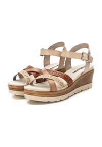 Sandalias de cuña beige y marrón con correas entrecruzadas, que presentan patrones recortados, una plantilla acolchada y una suela de goma.