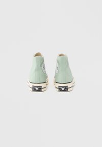 Αθλητικά παπούτσια ψηλού πάτου σε καμβά μέντας με μαύρες και λευκές λαστιχένιες σόλες. Διαθέτουν λογότυπο και αντίθετες μαύρες λεπτομέρειες στη σόλα.