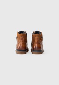 Bottines en cuir marron avec une finition lisse, un détail de sangle et une fermeture éclair sur le côté, avec une doublure intérieure bleue contrastante.